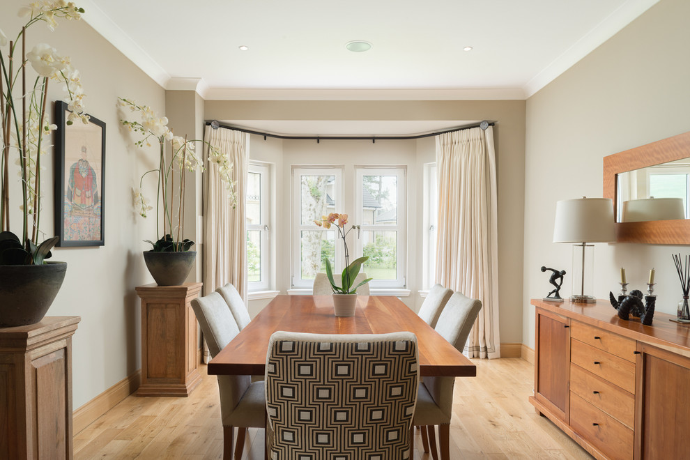 This is an example of a large traditional dining room in London with beige walls and light hardwood floors.