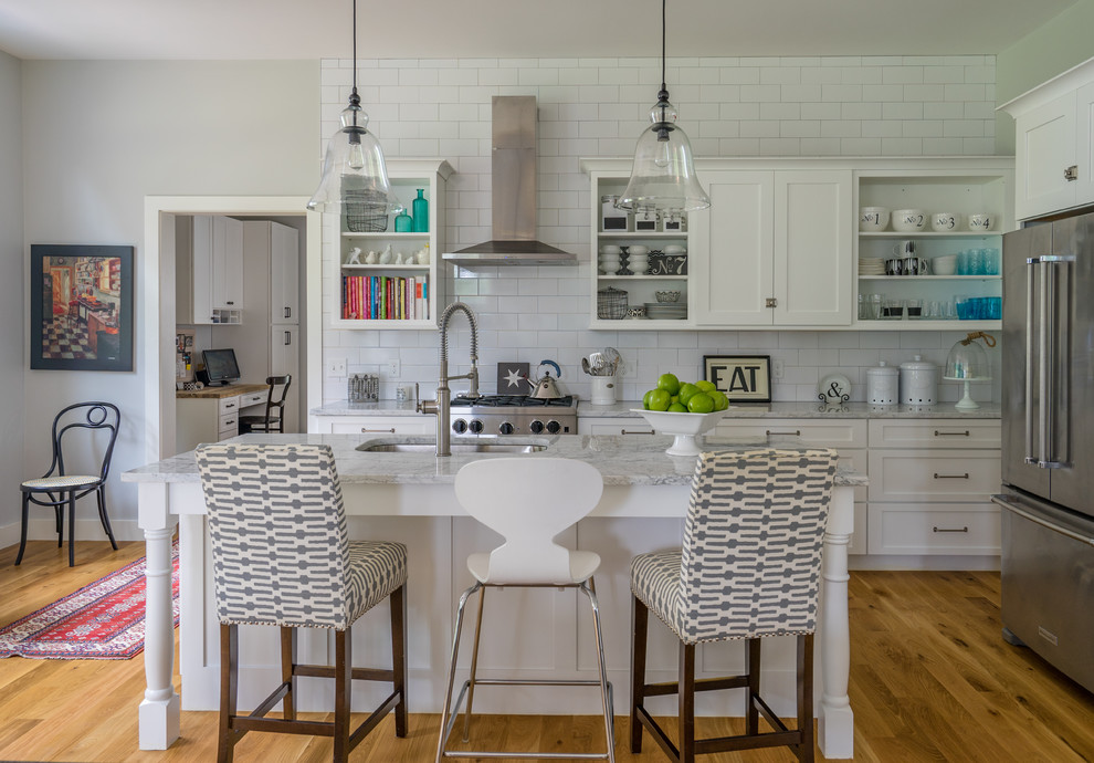 This is an example of a large country l-shaped open plan kitchen in Boston with shaker cabinets, white cabinets, marble benchtops, white splashback, subway tile splashback, stainless steel appliances, medium hardwood floors, with island, an undermount sink and brown floor.
