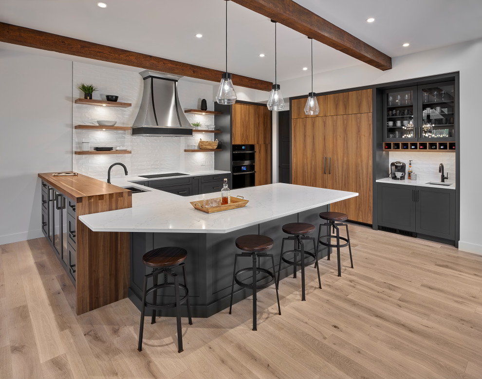 Design ideas for a mid-sized modern u-shaped open plan kitchen in Edmonton with an undermount sink, raised-panel cabinets, black cabinets, quartz benchtops, white splashback, black appliances, brown floor, white benchtop and exposed beam.