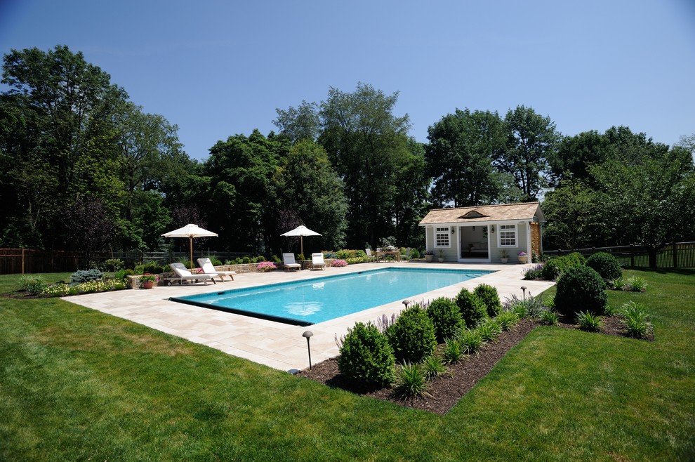 This is an example of a mid-sized traditional backyard rectangular lap pool in New York with a pool house and concrete pavers.