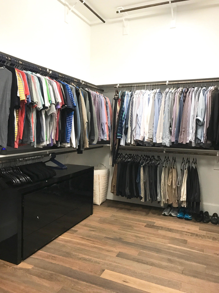 This is an example of a mid-sized transitional men's walk-in wardrobe in Houston with open cabinets, cork floors and brown floor.