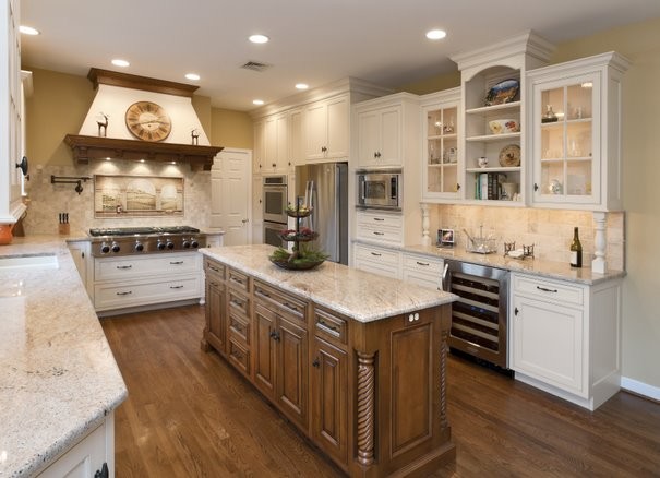 This is an example of a large traditional u-shaped separate kitchen in Philadelphia with an undermount sink, recessed-panel cabinets, white cabinets, granite benchtops, beige splashback, travertine splashback, stainless steel appliances, medium hardwood floors, with island, brown floor and beige benchtop.
