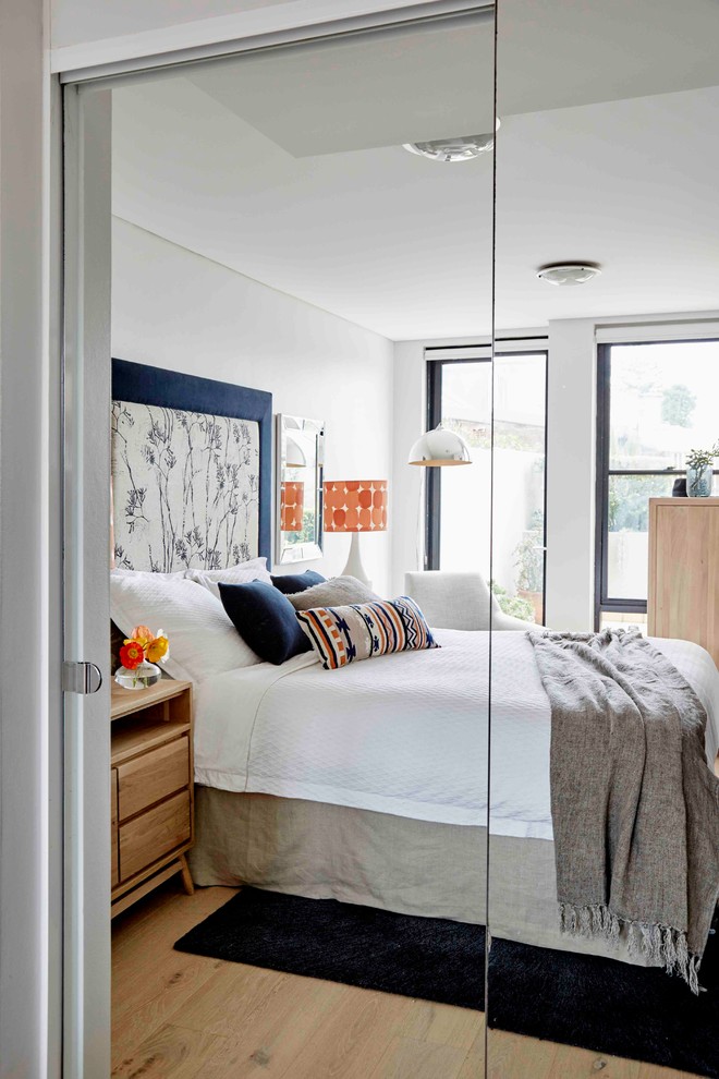 Small contemporary master bedroom in Sydney with grey walls and light hardwood floors.