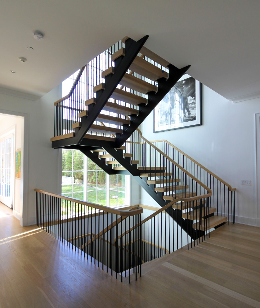 Photo of an expansive modern wood floating staircase in DC Metro with mixed railing and planked wall panelling.