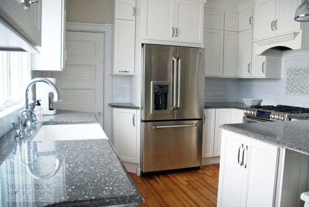 Eat-in kitchen - small transitional u-shaped light wood floor eat-in kitchen idea in Boston with a farmhouse sink, recessed-panel cabinets, white cabinets, quartz countertops, white backsplash, subway tile backsplash, stainless steel appliances and a peninsula