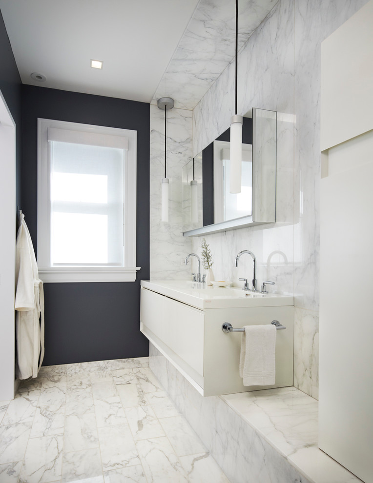 Modern bathroom in Chicago with an integrated sink, flat-panel cabinets, white cabinets, white tile, black walls, marble floors and marble.