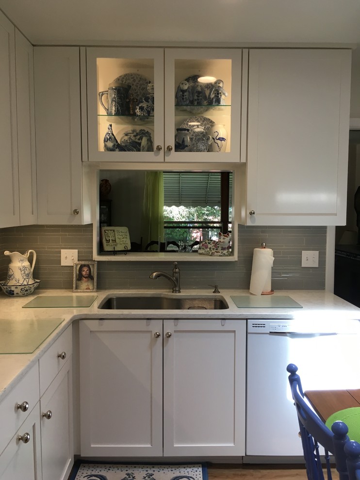 Inspiration for a mid-sized transitional u-shaped vinyl floor enclosed kitchen remodel with an undermount sink, shaker cabinets, white cabinets, quartz countertops, gray backsplash, glass tile backsplash, white appliances and no island