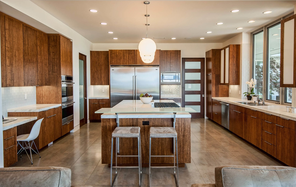 This is an example of a contemporary kitchen in Los Angeles with flat-panel cabinets, dark wood cabinets, beige splashback, stainless steel appliances and beige benchtop.