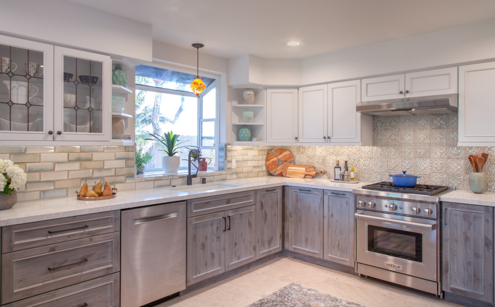 This is an example of a mid-sized transitional u-shaped eat-in kitchen in San Diego with a triple-bowl sink, shaker cabinets, distressed cabinets, quartz benchtops, blue splashback, ceramic splashback, stainless steel appliances, porcelain floors, a peninsula, white floor and white benchtop.