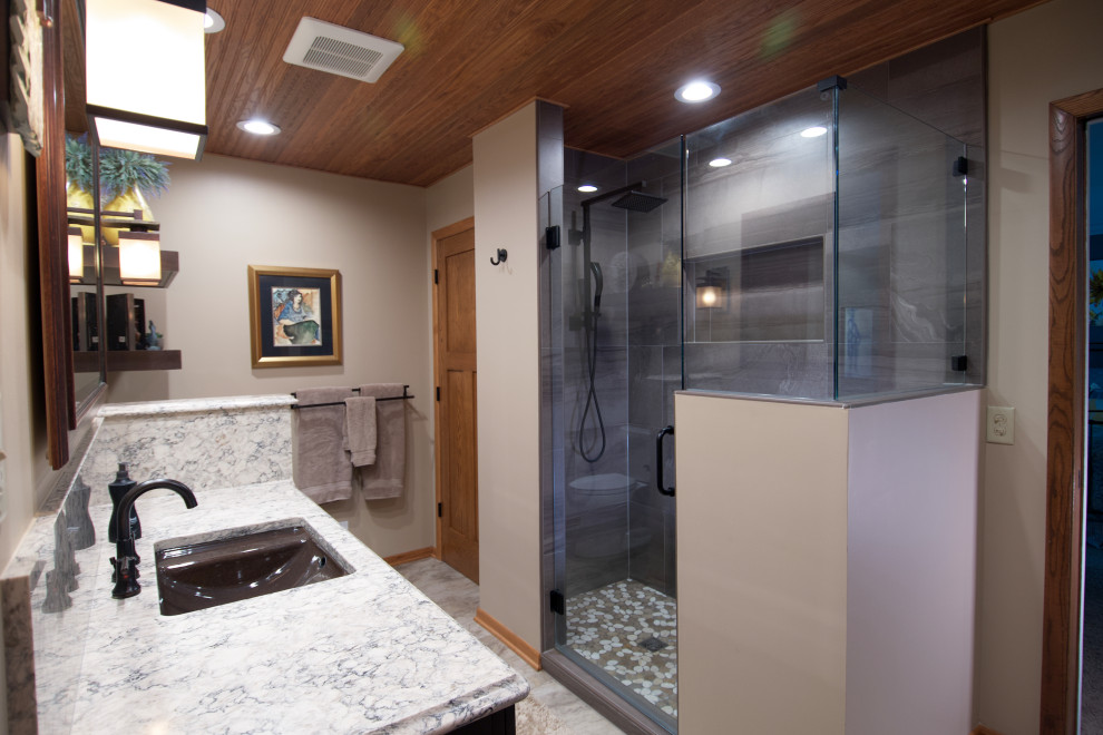 Idéer för mellanstora amerikanska vitt en-suite badrum, med luckor med infälld panel, bruna skåp, grå kakel, keramikplattor, beige väggar, klinkergolv i keramik, ett undermonterad handfat, bänkskiva i kvarts, beiget golv och dusch med gångjärnsdörr