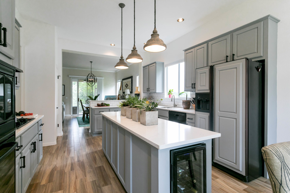 Example of a transitional u-shaped porcelain tile and brown floor eat-in kitchen design in Austin with a double-bowl sink, gray cabinets, quartz countertops, white backsplash, ceramic backsplash, black appliances and an island