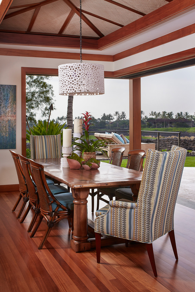 Inspiration for a tropical dining room in Hawaii with white walls and dark hardwood floors.