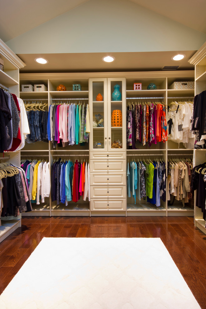 This is an example of a large traditional women's walk-in wardrobe in New York with raised-panel cabinets, white cabinets and dark hardwood floors.