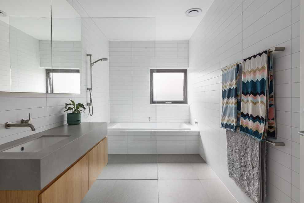 Design ideas for a contemporary wet room bathroom in Melbourne with flat-panel cabinets, medium wood cabinets, a drop-in tub, white tile, an undermount sink, grey floor, grey benchtops, a single vanity and a floating vanity.