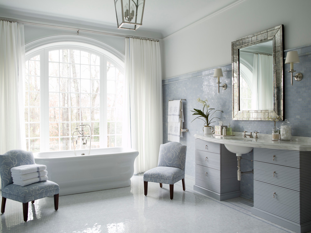Inspiration for a traditional master bathroom in Charlotte with blue cabinets, a freestanding tub, blue tile, blue walls, an undermount sink, marble benchtops, mosaic tile and flat-panel cabinets.