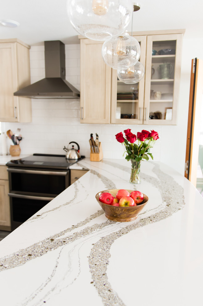 Enclosed kitchen - mid-sized transitional u-shaped vinyl floor and brown floor enclosed kitchen idea with an undermount sink, flat-panel cabinets, beige cabinets, quartz countertops, white backsplash, subway tile backsplash, black appliances, a peninsula and white countertops