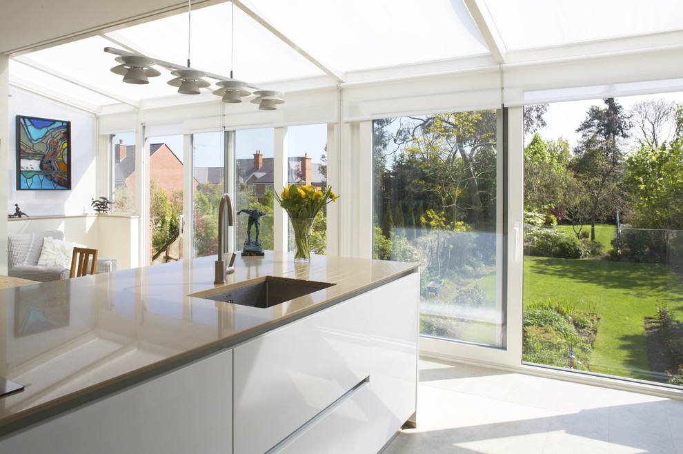 This is an example of a contemporary eat-in kitchen in Dublin with an undermount sink, flat-panel cabinets and white cabinets.