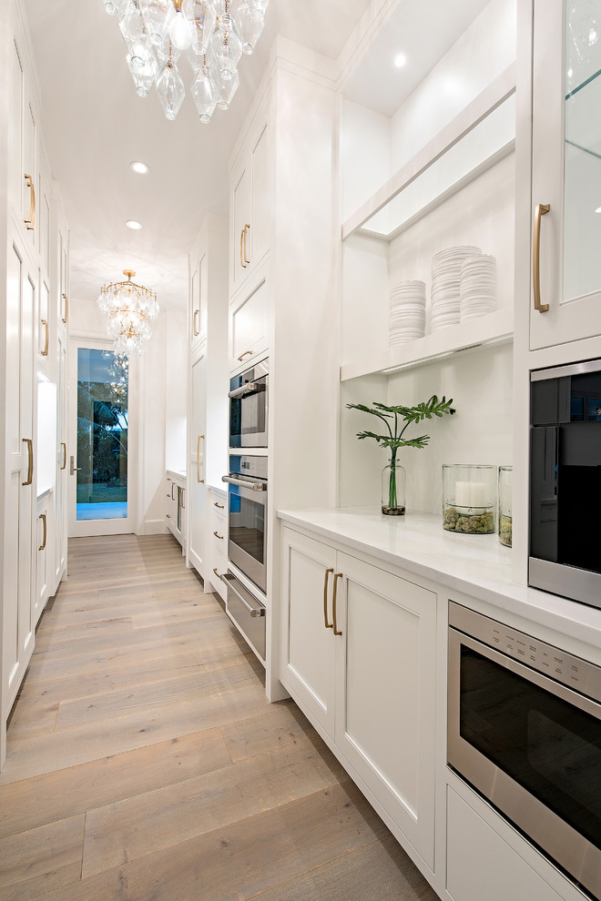 Inspiration for a large transitional u-shaped light wood floor and beige floor kitchen remodel with an undermount sink, beaded inset cabinets, white cabinets, quartzite countertops, white backsplash, stone slab backsplash, paneled appliances, an island and white countertops