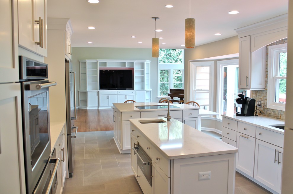Inspiration for a large transitional porcelain tile and brown floor kitchen remodel in DC Metro with an undermount sink, white cabinets, beige backsplash, stainless steel appliances, shaker cabinets, quartzite countertops, stone tile backsplash and two islands