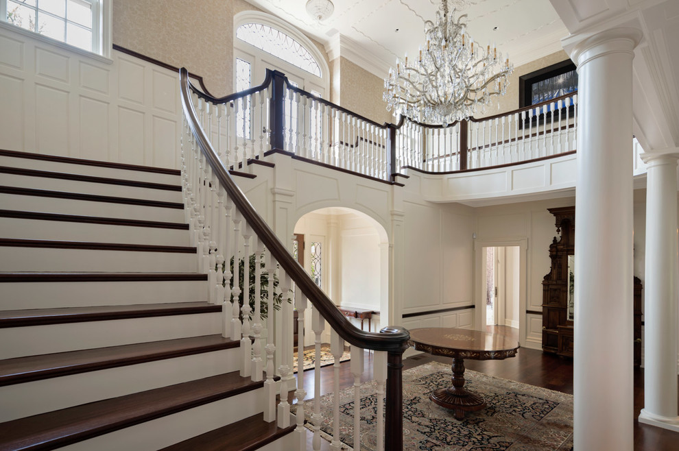 This is an example of a large traditional wood curved staircase in Philadelphia with wood risers and wood railing.
