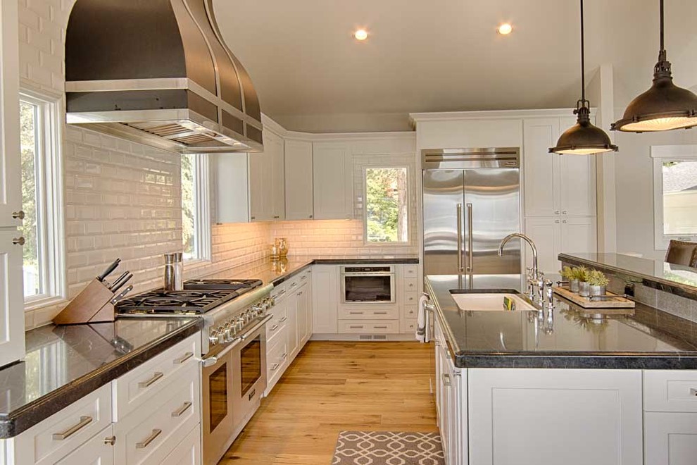 Large transitional galley eat-in kitchen in Seattle with a single-bowl sink, shaker cabinets, white cabinets, soapstone benchtops, white splashback, subway tile splashback, stainless steel appliances, light hardwood floors and with island.