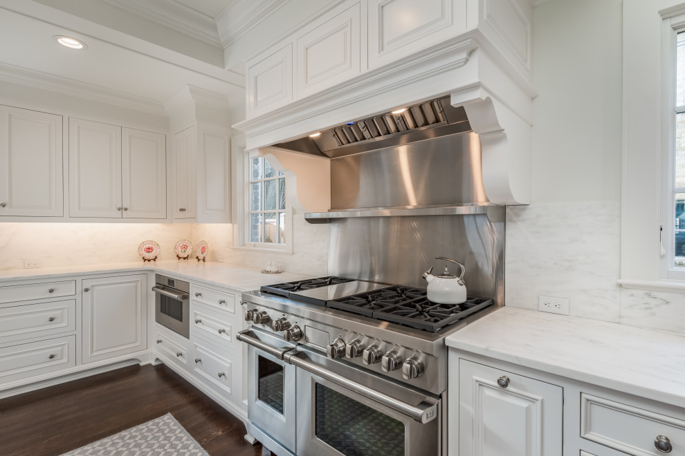 Inspiration for a large transitional l-shaped medium tone wood floor and brown floor open concept kitchen remodel in Milwaukee with an undermount sink, recessed-panel cabinets, white cabinets, marble countertops, white backsplash, marble backsplash, stainless steel appliances, an island and white countertops