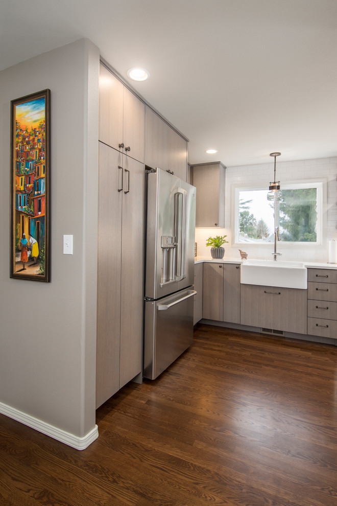 Inspiration for a mid-sized transitional l-shaped dark wood floor and brown floor open concept kitchen remodel in Seattle with a farmhouse sink, flat-panel cabinets, gray cabinets, quartzite countertops, white backsplash, subway tile backsplash, stainless steel appliances and an island
