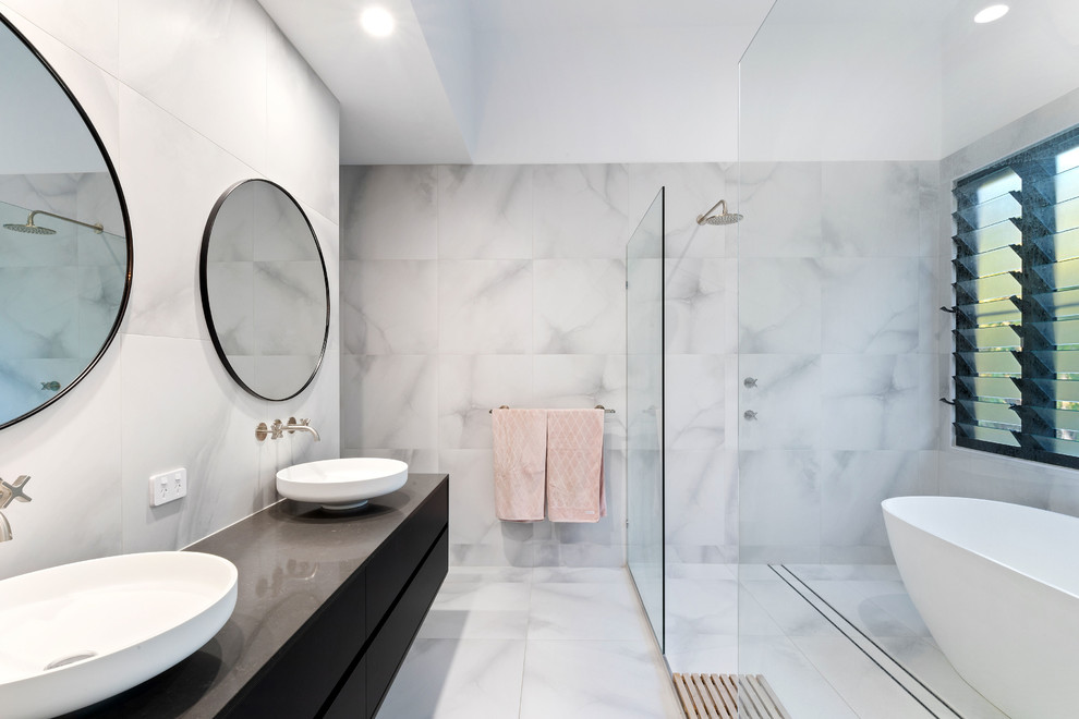 Inspiration for a large beach style master wet room bathroom in Sunshine Coast with flat-panel cabinets, black cabinets, a freestanding tub, marble, white walls, porcelain floors, a vessel sink, granite benchtops, grey floor, an open shower, black benchtops and gray tile.
