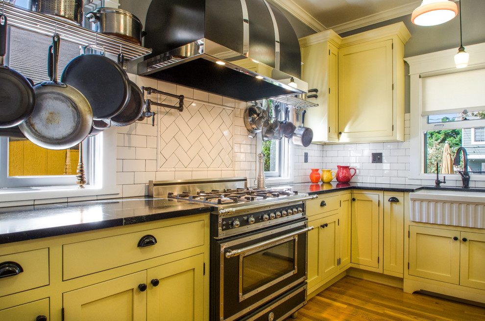 Small midcentury galley separate kitchen in Orange County with a farmhouse sink, raised-panel cabinets, yellow cabinets, granite benchtops, white splashback, subway tile splashback, panelled appliances, medium hardwood floors and with island.