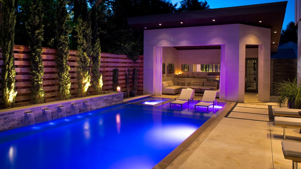 Photo of a mid-sized modern courtyard rectangular infinity pool in Dallas with a pool house and decking.