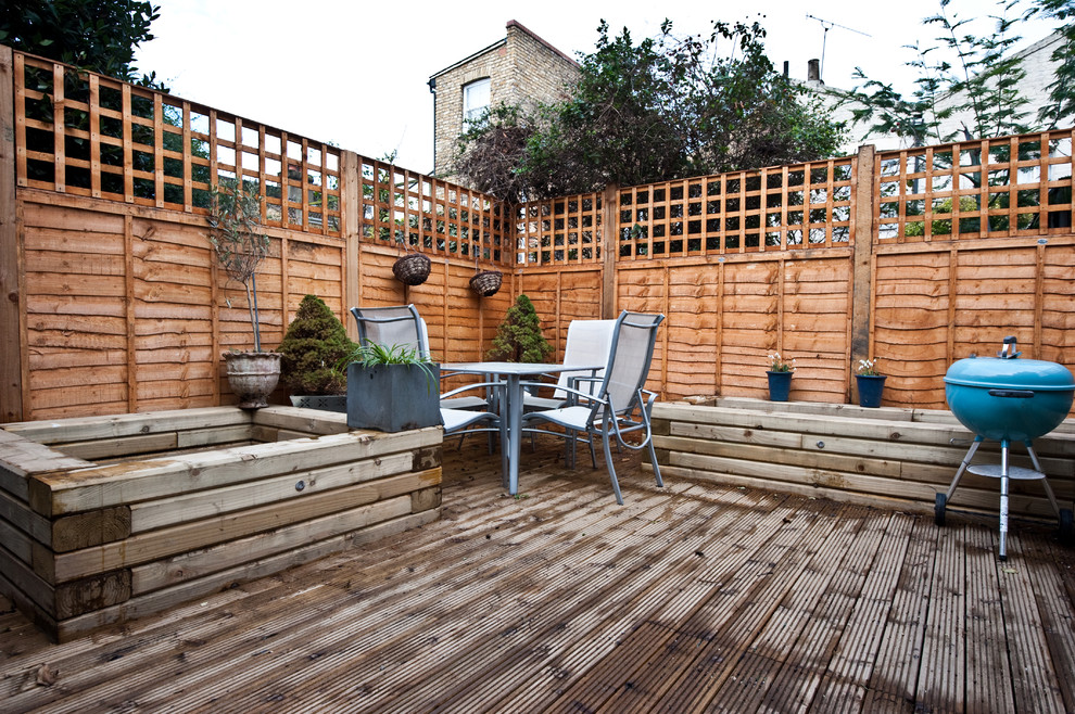 Photo of a large contemporary backyard deck in London with a container garden and a pergola.
