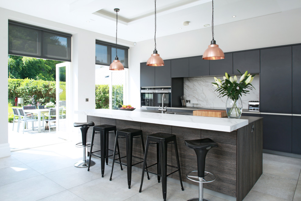 Medium sized contemporary single-wall kitchen/diner in Other with a built-in sink, flat-panel cabinets, black cabinets, composite countertops, white splashback, marble splashback, stainless steel appliances and an island.