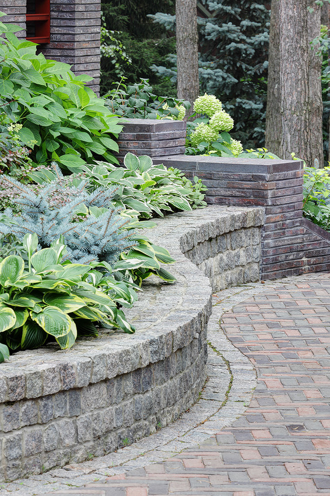 This is an example of a country garden in Moscow with a retaining wall and brick pavers.