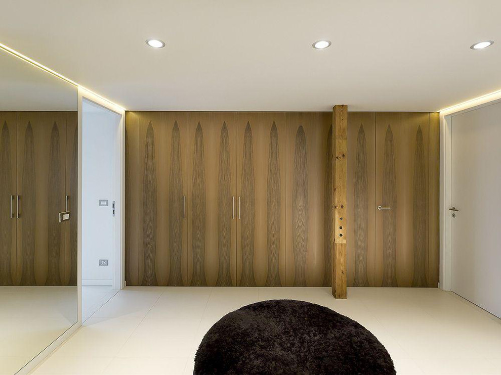 This is an example of a large modern storage and wardrobe in Paris with beaded inset cabinets, dark wood cabinets, concrete floors and beige floor.