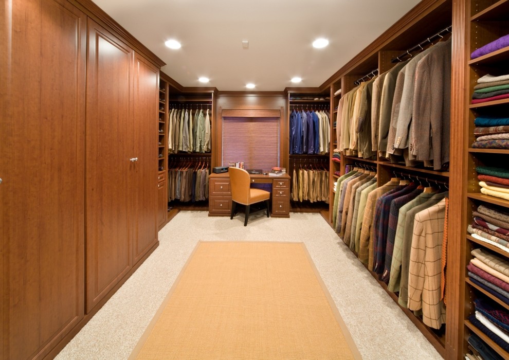 This is an example of an expansive contemporary men's walk-in wardrobe in Chicago with raised-panel cabinets, medium wood cabinets and carpet.