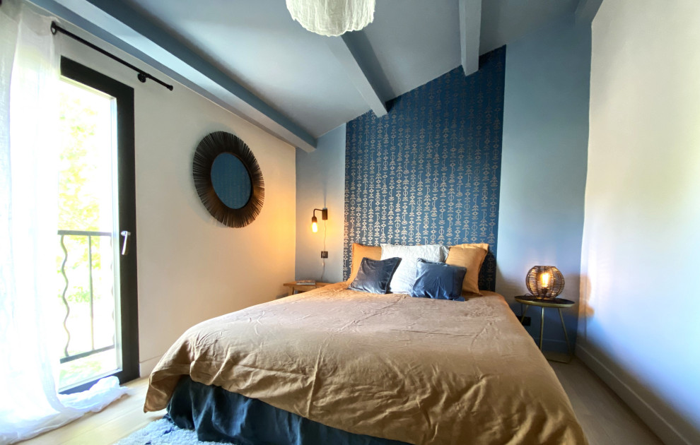 Cette photo montre une chambre mansardée ou avec mezzanine moderne de taille moyenne avec un mur bleu, parquet clair, poutres apparentes et du papier peint.