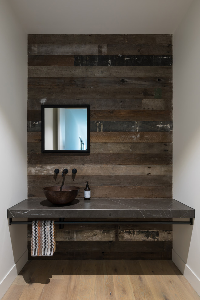 Photo of a mid-sized industrial bathroom in Auckland with open cabinets, grey cabinets, multi-coloured walls, light hardwood floors, granite benchtops, brown floor and grey benchtops.