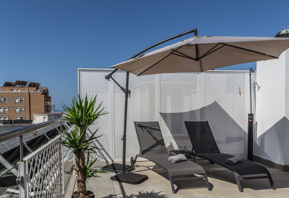 Large scandinavian rooftop deck in Other with an outdoor shower, an awning and glass railing.