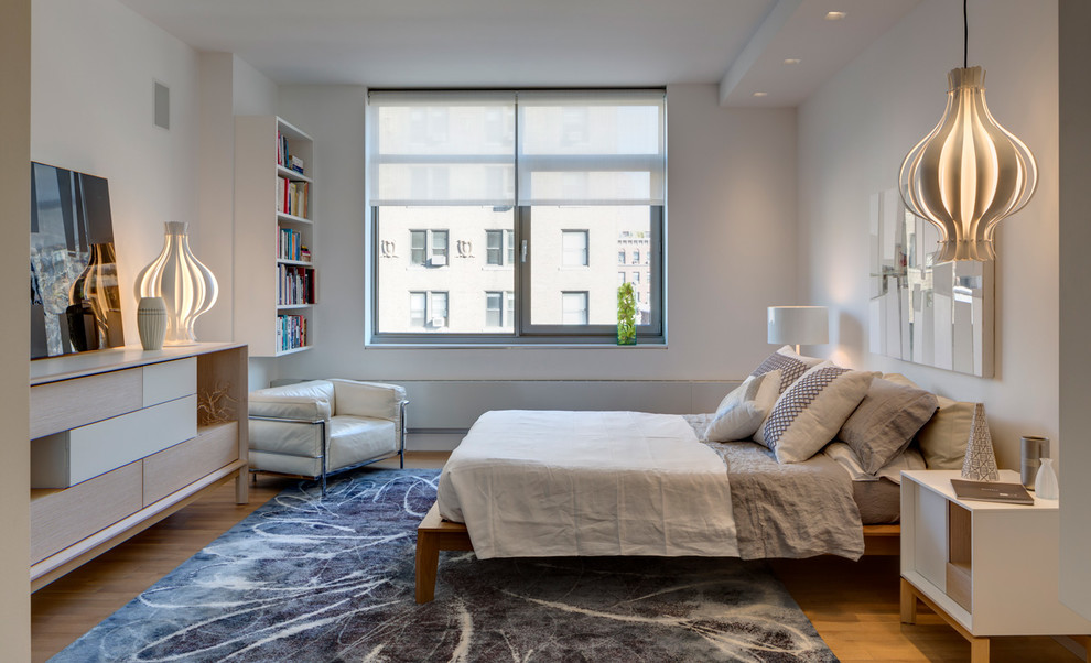 Contemporary bedroom in New York with white walls, light hardwood floors and blue floor.