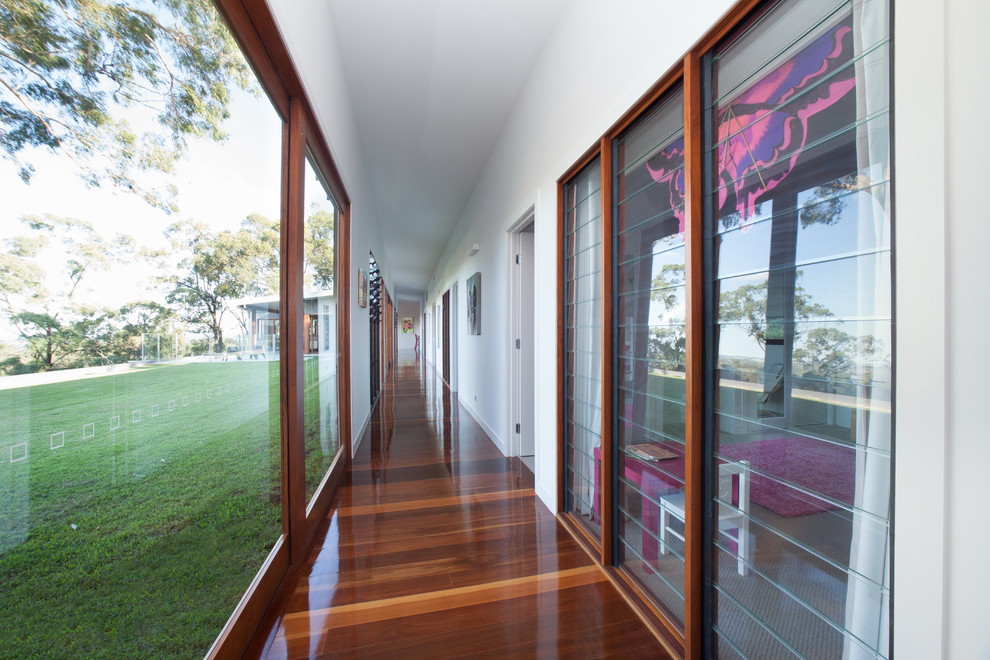This is an example of a large contemporary hallway in Brisbane with white walls and dark hardwood floors.