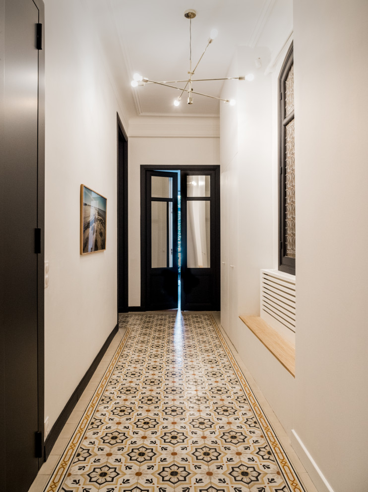 Cette photo montre un grand couloir avec un mur blanc et un sol multicolore.