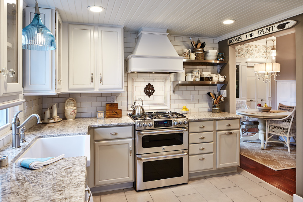 Photo of a small traditional l-shaped eat-in kitchen in St Louis with a farmhouse sink, raised-panel cabinets, white cabinets, granite benchtops, white splashback, subway tile splashback, stainless steel appliances, porcelain floors, no island, beige floor and multi-coloured benchtop.