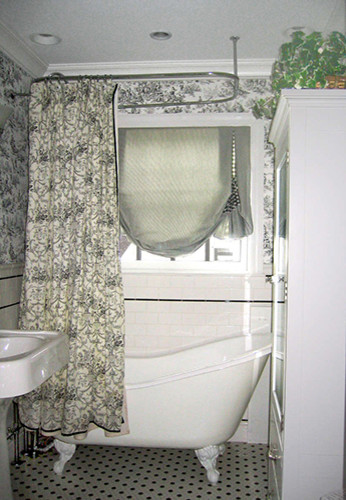 Mid-sized country 3/4 bathroom in New York with open cabinets, white cabinets, a claw-foot tub, a shower/bathtub combo, a one-piece toilet, black tile, ceramic tile, white walls, ceramic floors and a pedestal sink.