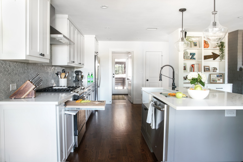 Small midcentury single-wall eat-in kitchen in Dallas with a farmhouse sink, flat-panel cabinets, white cabinets, granite benchtops, grey splashback, granite splashback, black appliances, dark hardwood floors, with island, brown floor and white benchtop.