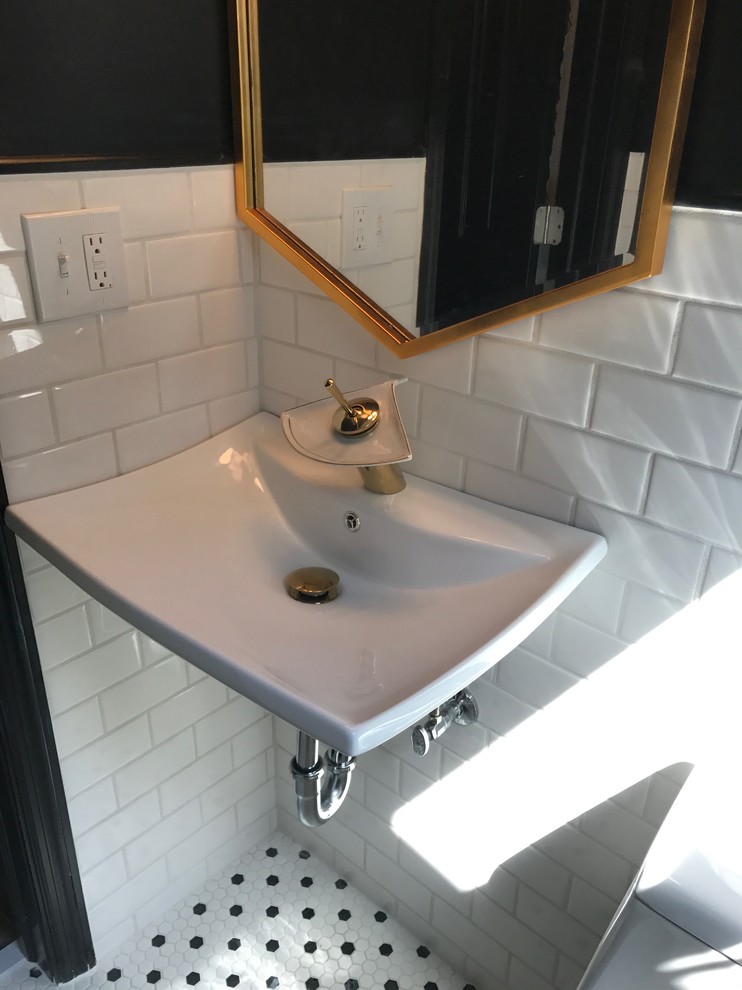 This is an example of a small midcentury bathroom in New York with a one-piece toilet, white tile, subway tile, black walls, ceramic floors, a wall-mount sink and white floor.
