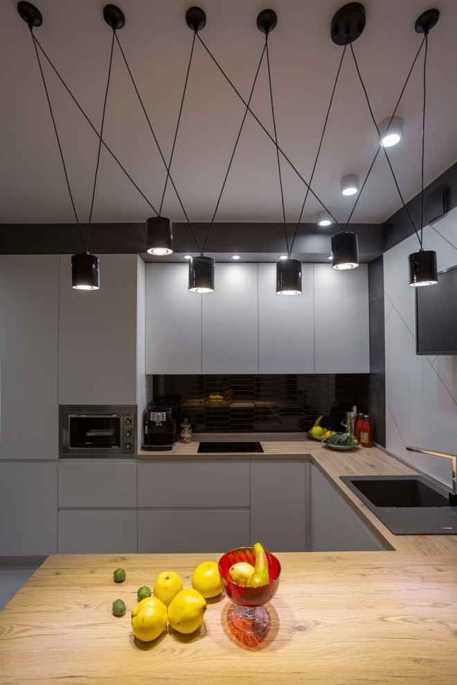 Mid-sized trendy u-shaped porcelain tile and gray floor eat-in kitchen photo in Yekaterinburg with a drop-in sink, flat-panel cabinets, white cabinets, laminate countertops, black backsplash, porcelain backsplash, stainless steel appliances, a peninsula and brown countertops