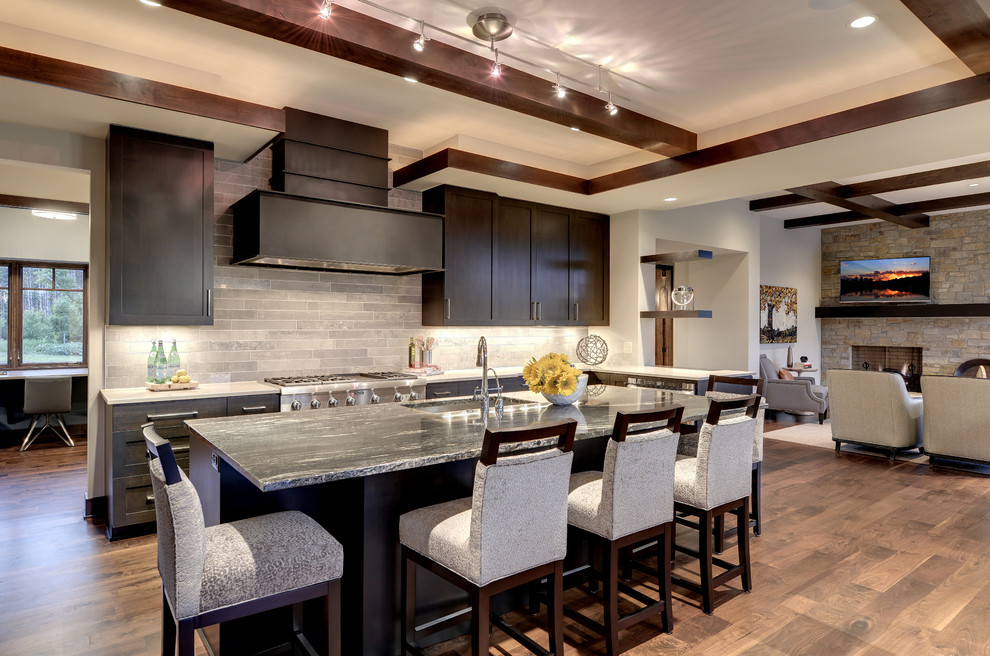 Photo of a transitional open plan kitchen in Minneapolis with an undermount sink, shaker cabinets, dark wood cabinets, grey splashback and stainless steel appliances.