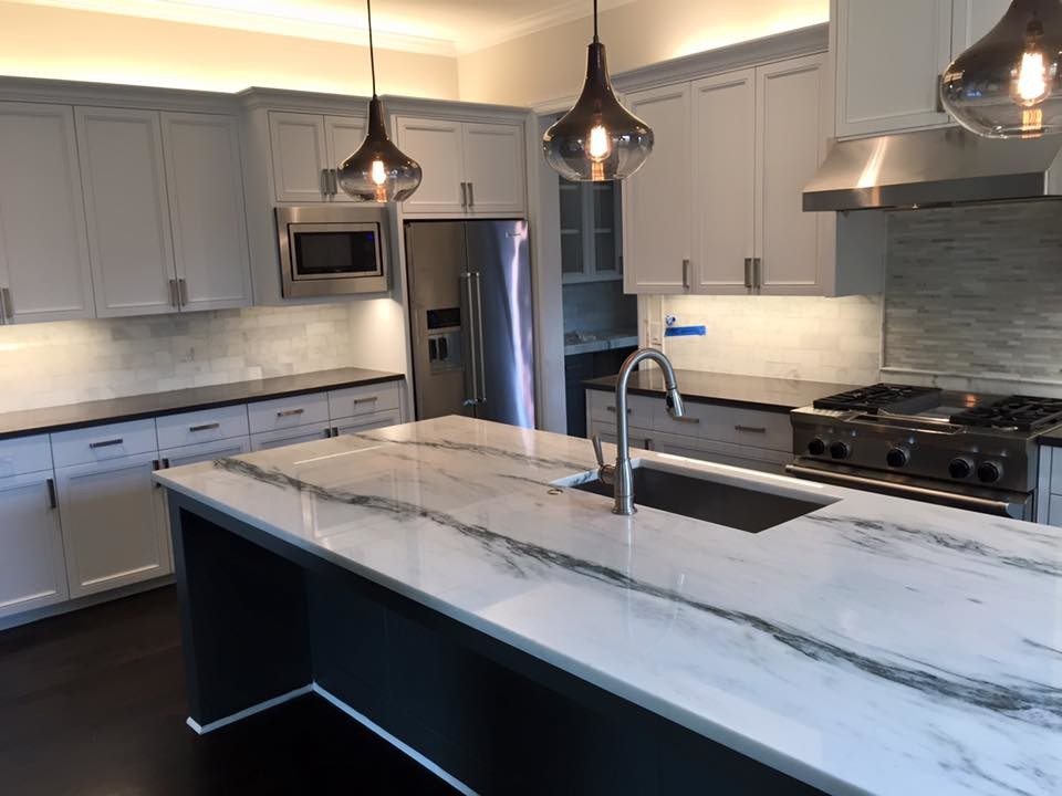Example of a mid-sized transitional single-wall dark wood floor open concept kitchen design in Dallas with recessed-panel cabinets, white cabinets, marble countertops, white backsplash, stone tile backsplash, stainless steel appliances and an island