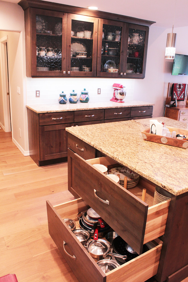 Inspiration for a large rustic u-shaped light wood floor and brown floor open concept kitchen remodel in Boise with an undermount sink, shaker cabinets, brown cabinets, granite countertops, white backsplash, glass tile backsplash, stainless steel appliances and an island