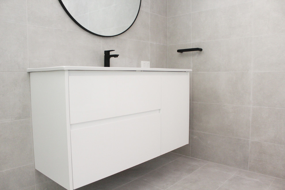 This is an example of a large modern master bathroom in Perth with flat-panel cabinets, white cabinets, a corner shower, gray tile, porcelain tile, grey walls, porcelain floors, an integrated sink, stainless steel benchtops, grey floor, a hinged shower door and white benchtops.